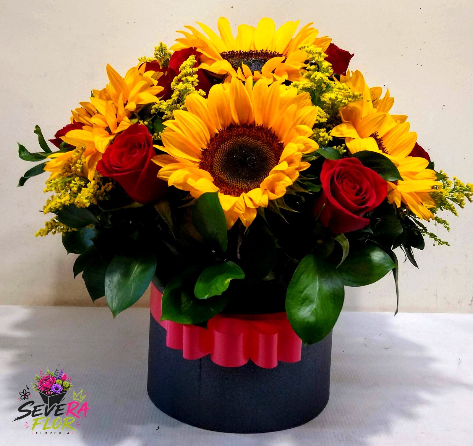 Severo Girasol: Girasoles y rosas en cilindro negro. Cajas Florales Severa Flor Bogotá